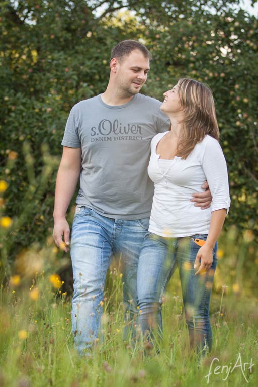 Paarshooting mit fenjArt Fotografie ein junges paar laeuft arm in arm durch eine sommerliche wiese